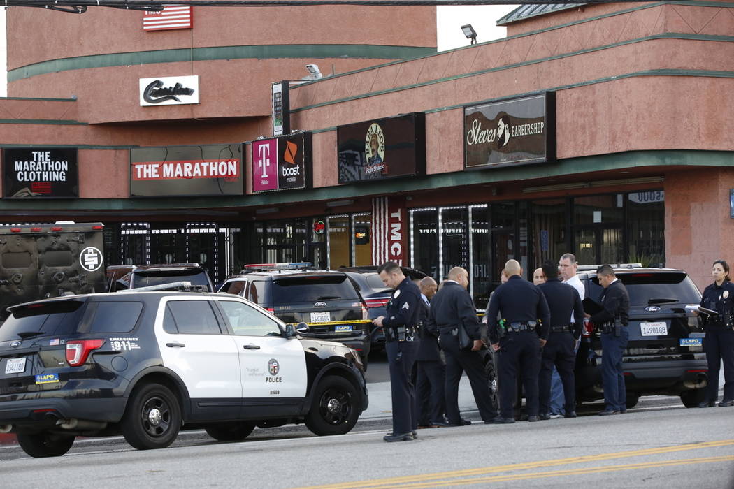 Police investigators gather around the Marathon Clothing store of rapper Nipsey Hussle in Los A ...