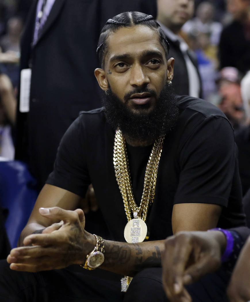 In this March 29, 2018, photo, rapper Nipsey Hussle watches an NBA basketball game between the ...