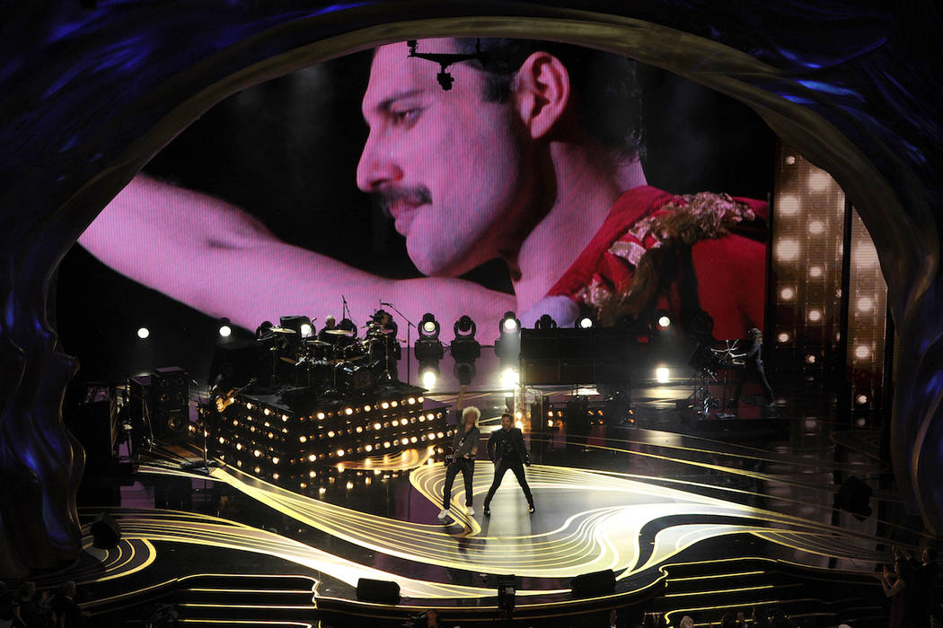 An image of Freddie Mercury appears on screen as Brian May, left, and Adam Lambert of Queen per ...