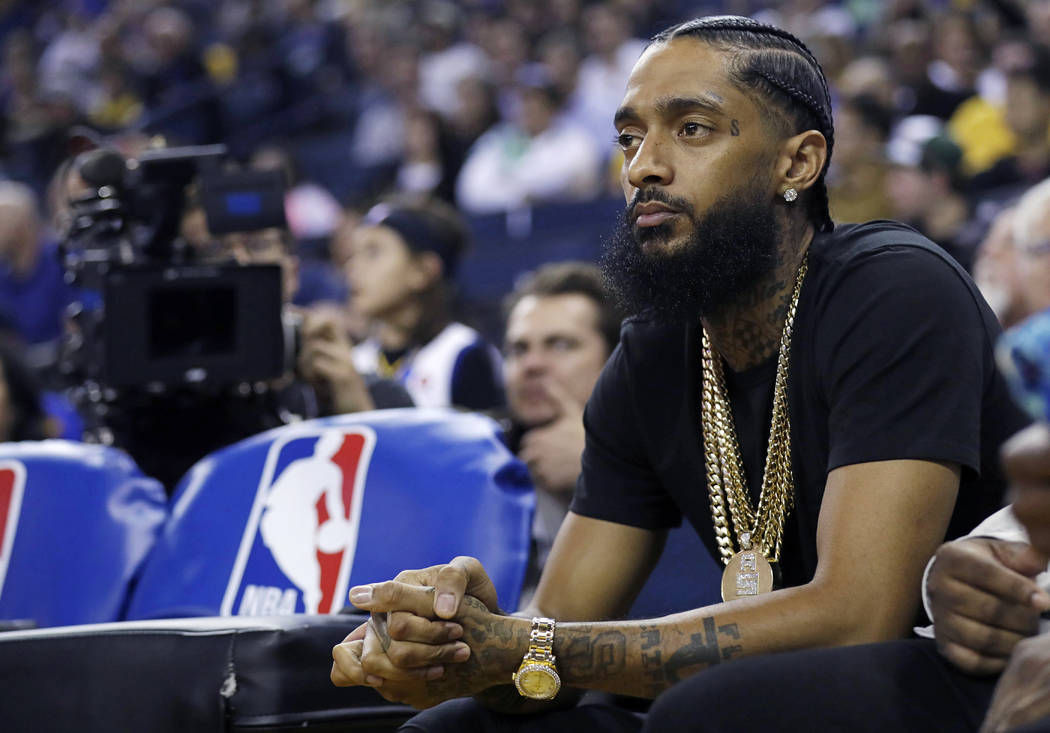 In this March 29, 2018, file photo, rapper Nipsey Hussle watches an NBA basketball game between ...