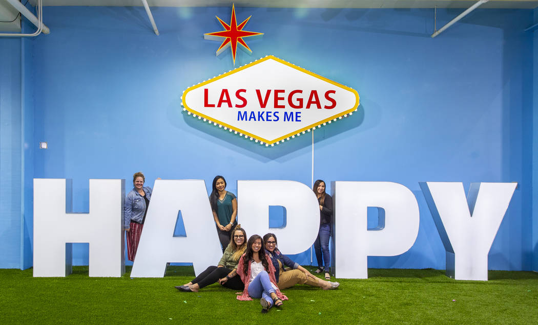 Friends strike poses about the signs in the Happy Room at the new Happy Place popup at Mandalay ...