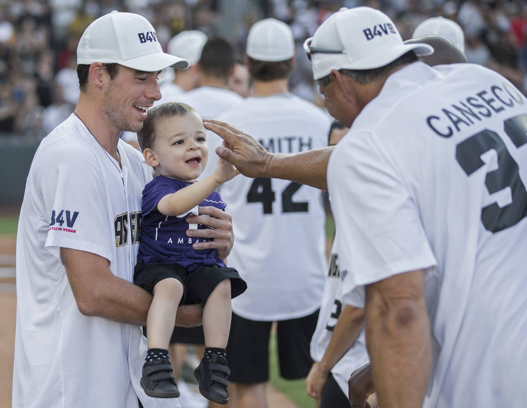Golden Knights right wing Reilly Smith, left, holds Jordan Rey, 2, as he gets a high five from ...