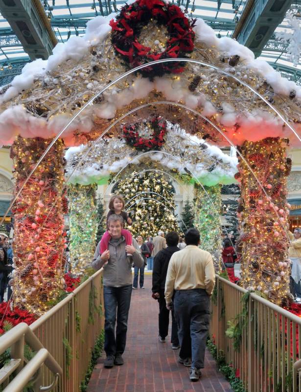 Las Vegas resident Robert Kilpatrick and his 3-year-old daughter, Marley, pass under decorated ...