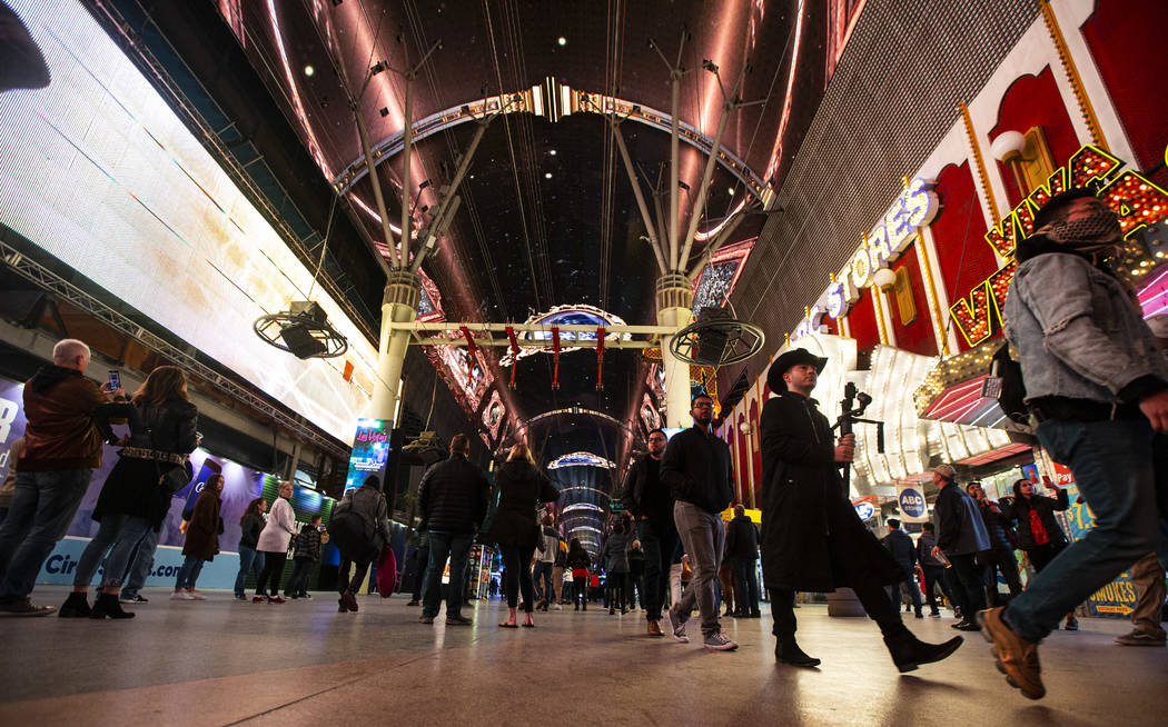 People walk below the recently-upgraded Viva Vision screen as a video highlighting The Killers ...
