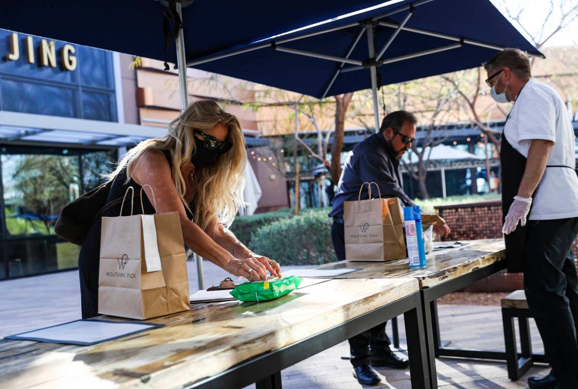 Zetta Magliarditi, left, reaches for a sanitizing wipe while picking up food at Wolfgang Puck P ...