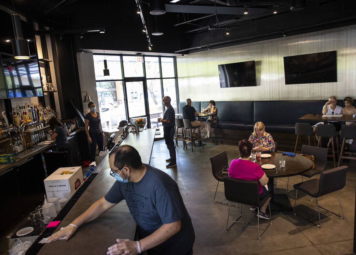 People dine as the bar area is sanitized at Wolfgang Puck Players Locker while some restaurants ...