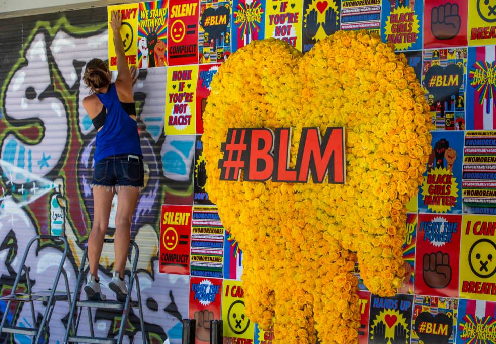 Cynthia Hartness attaches one of about 180 BLM posters to the facade of the Majestic Repertory ...