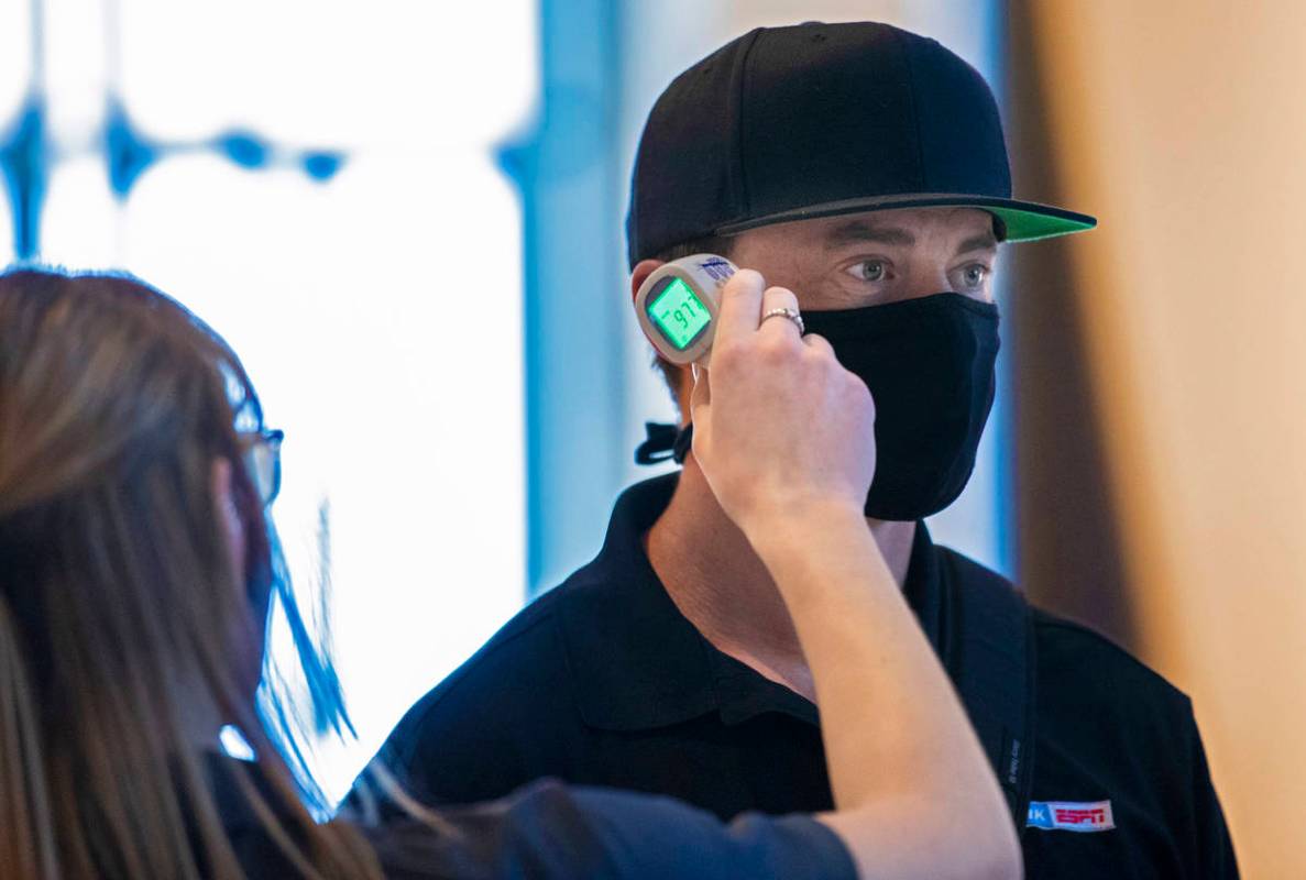Emergency medical technician Megan Meyer, left, takes Thomas Stewart's temperature as he enters ...