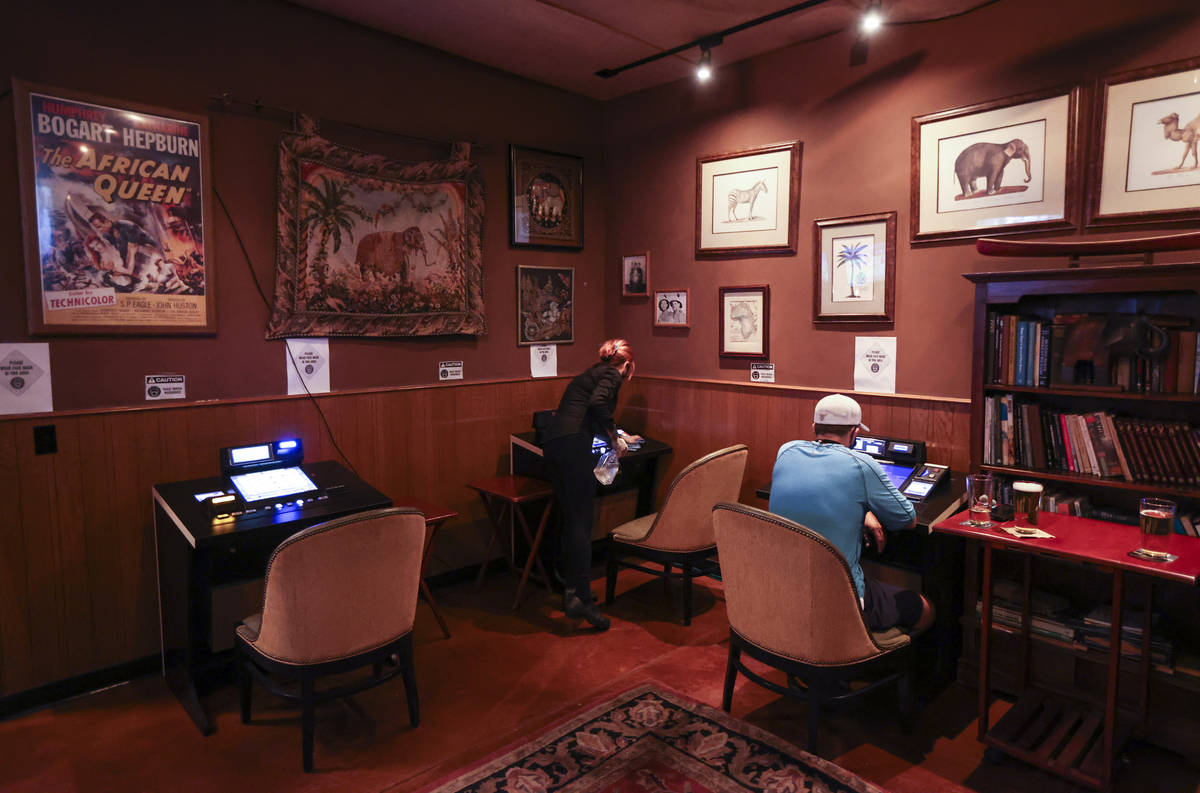 Bartender Silken Widmer sanitizes a gaming device in a lounge area at Black Mountain Grill in H ...