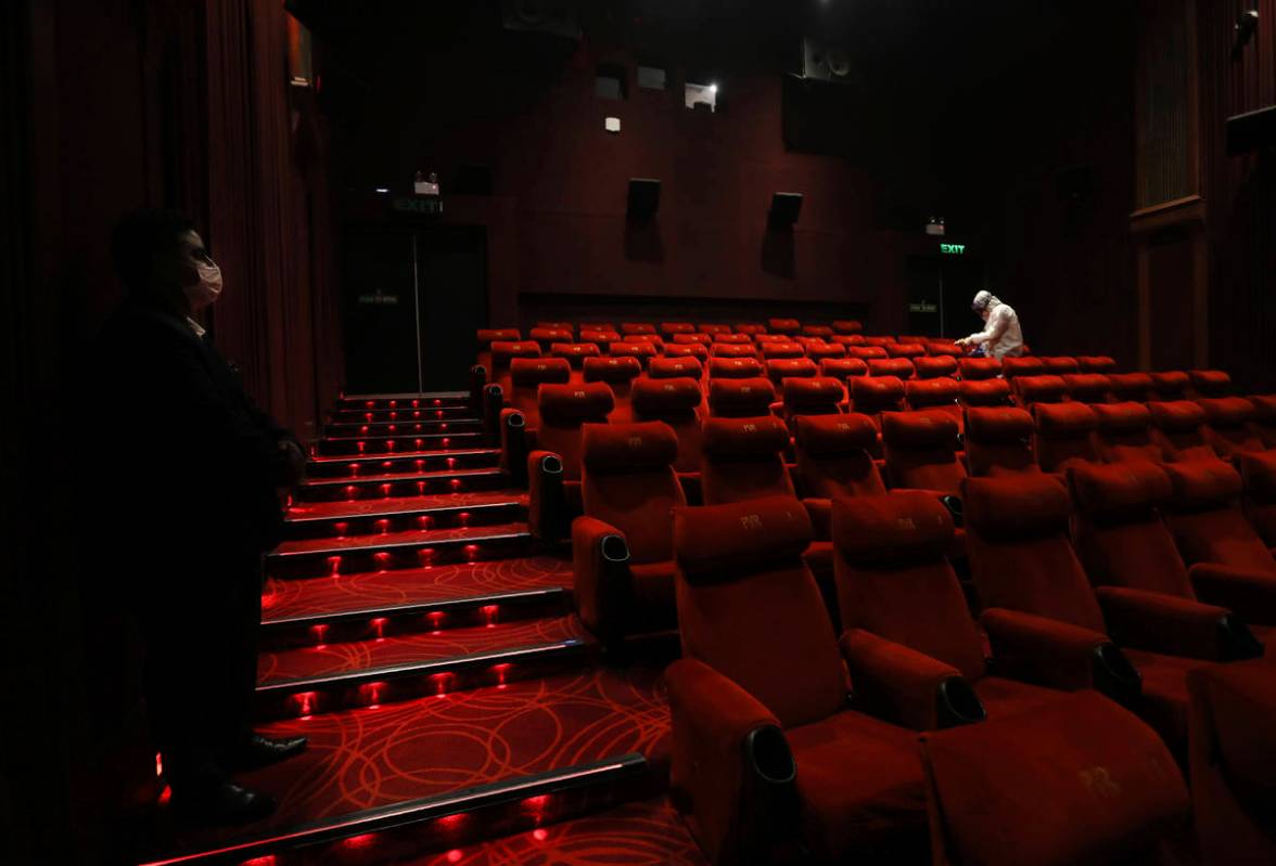 Workers of PVR cinemas, a multiplex cinema chain,sanitizes a theater during a press preview to ...