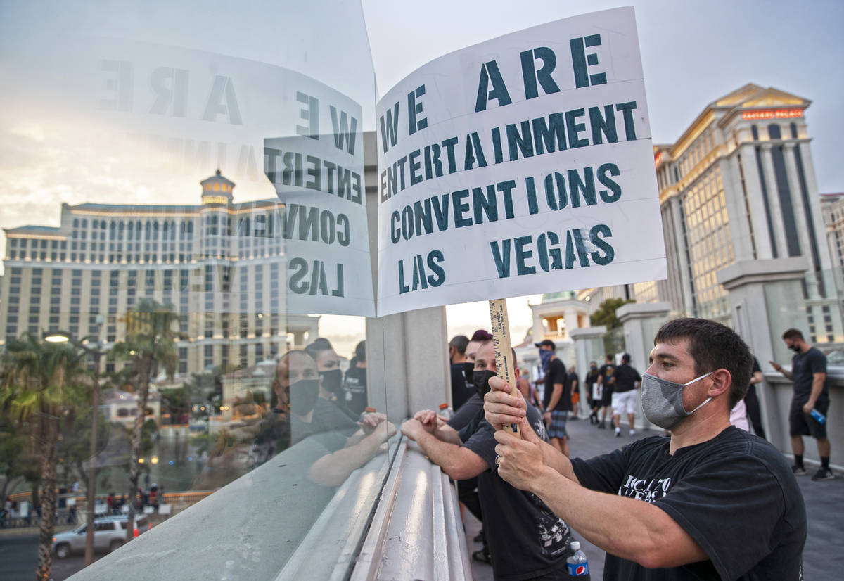 Leandro Esqueda holds a sign on a pedestrian bridge while watching a motorcade of his peers pas ...