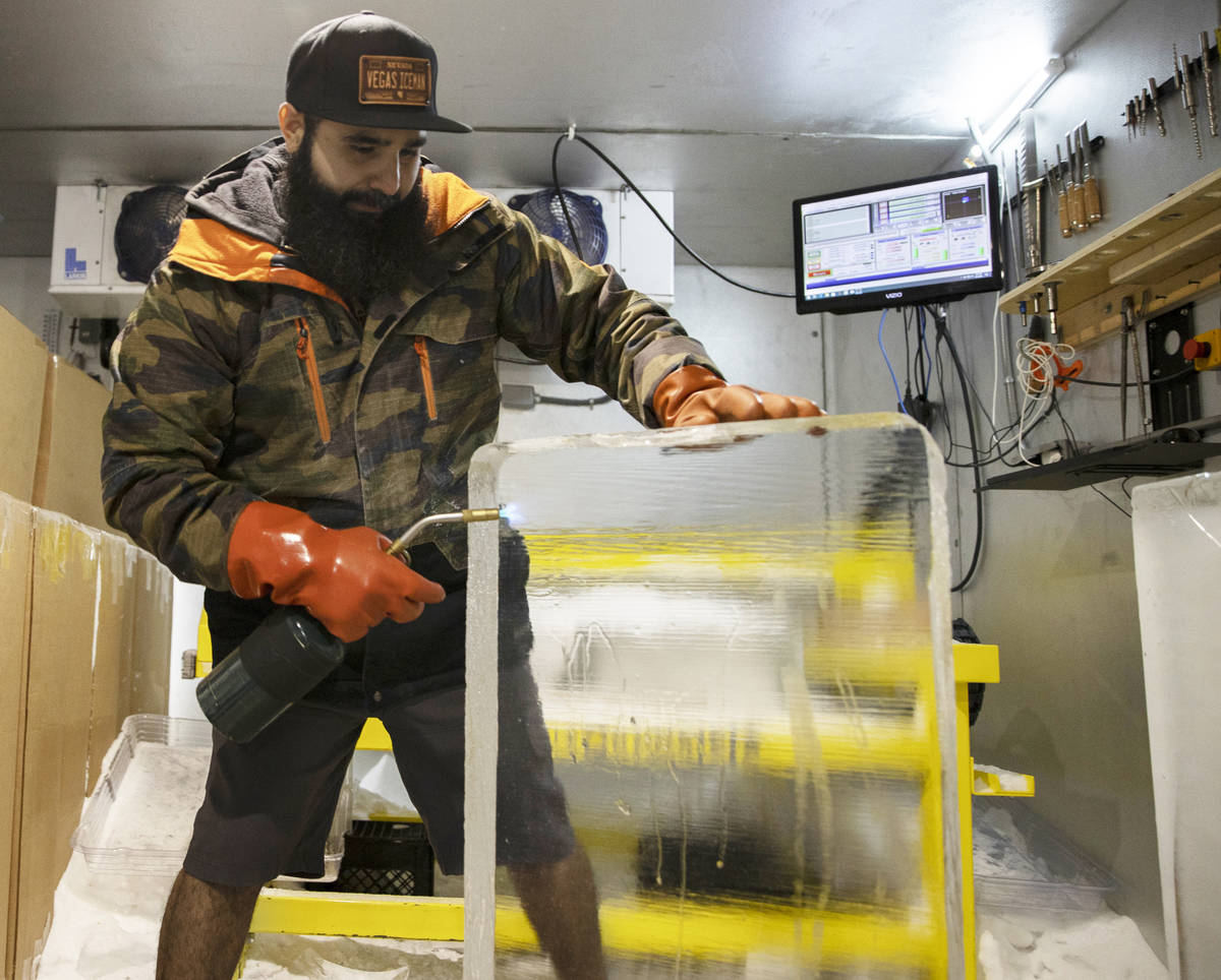 Marco Villarreal, known as "Vegas Ice Man," uses a torch to prep a fresh ice block on ...