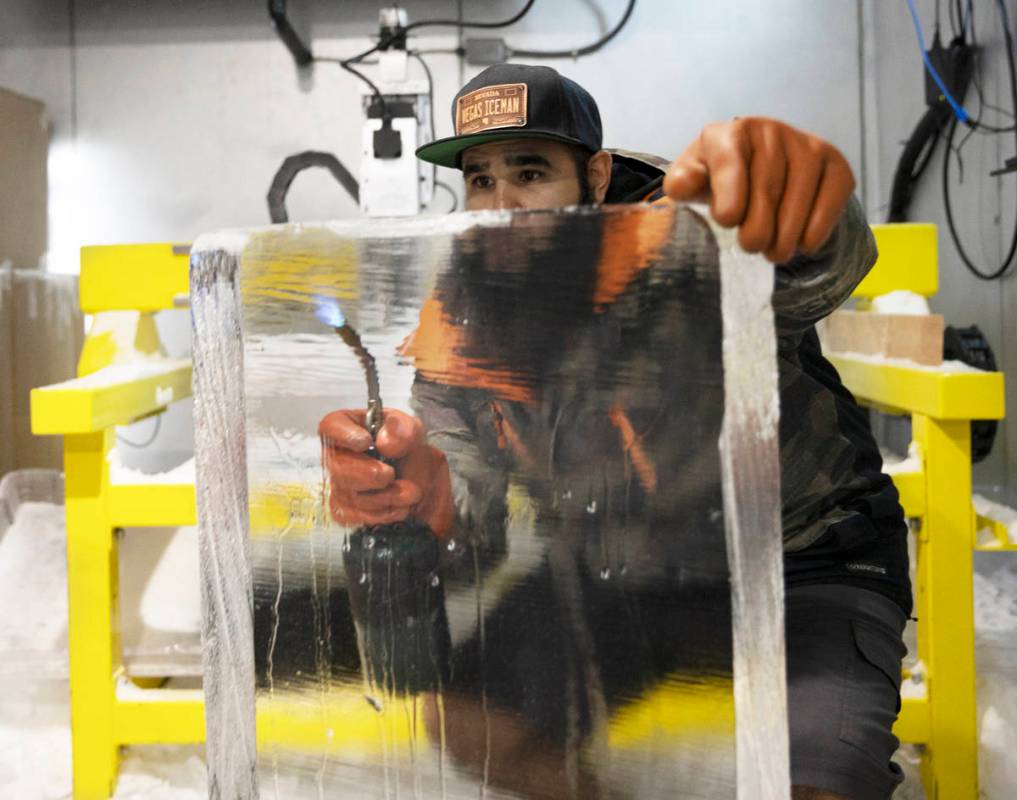Marco Villarreal, known as "Vegas Ice Man," uses a torch to prep a fresh ice block on ...