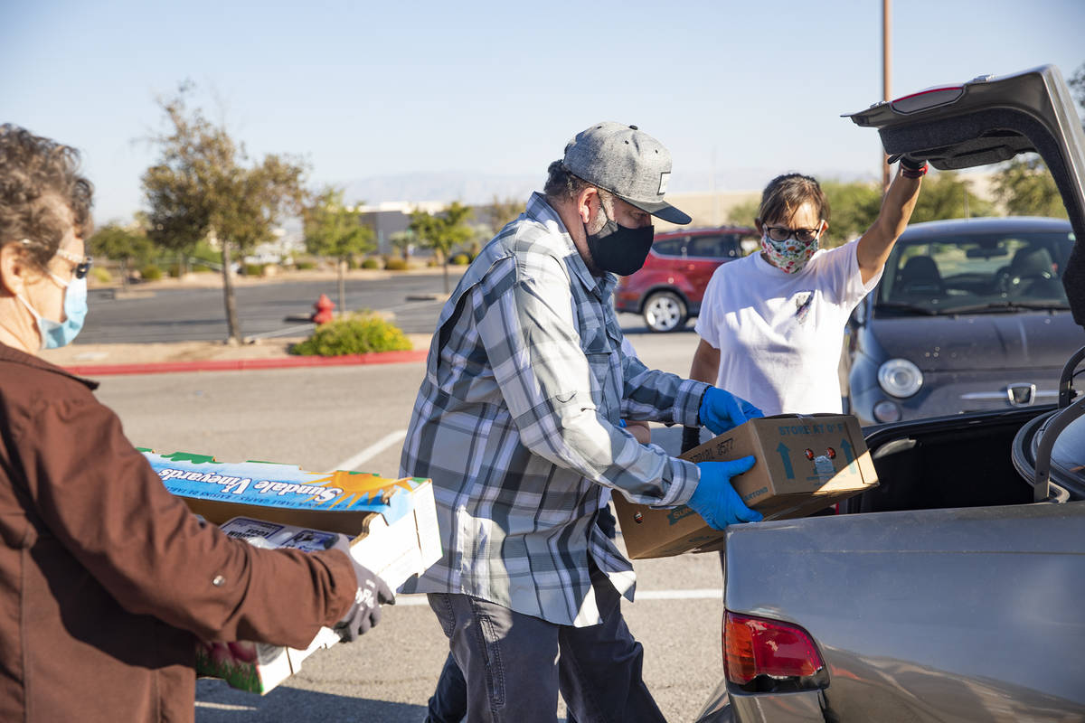 Volunteers Christina Bailey, from left, Huberto Sandoval, and Liz Hubbard help place food in th ...