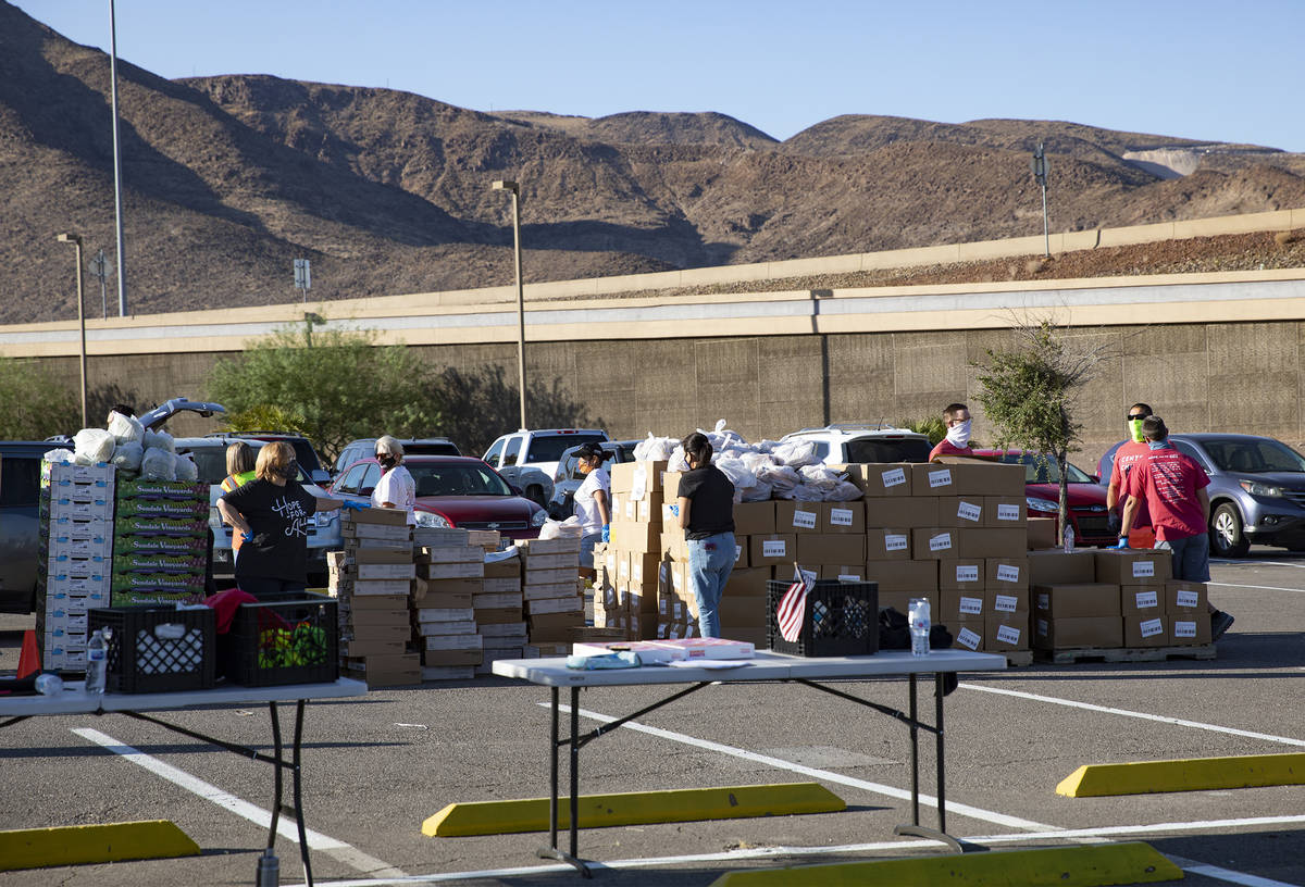 Volunteers wait for people at the new drive-thru distribution site for Three Square, Southern N ...
