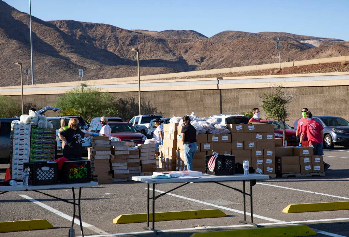 Volunteers wait for people at the new drive-thru distribution site for Three Square, Southern N ...