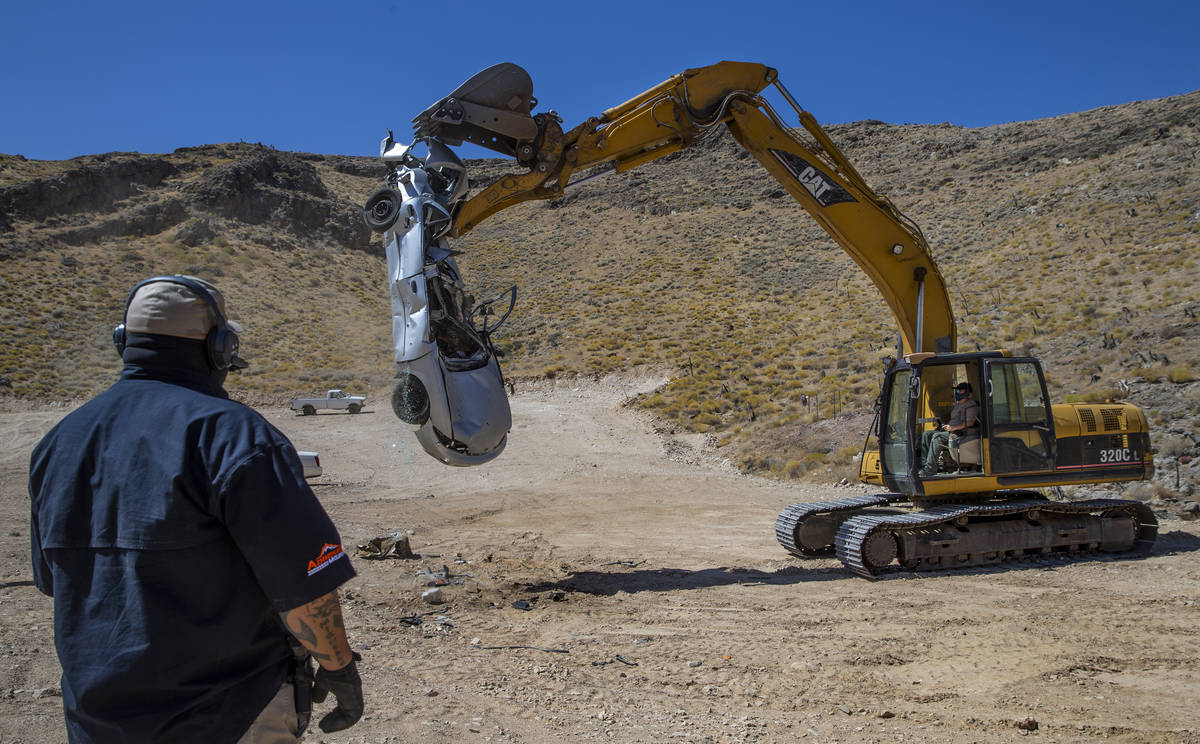 Sam Davidson, left, uses a two-way radio to instruct Christopher Lawrence as he releases a car ...
