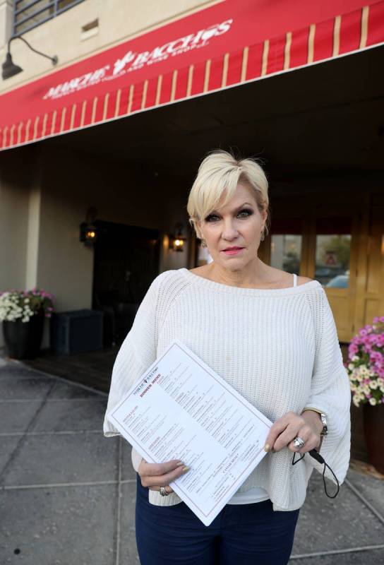 Rhonda Wyatt, co-owner of Marche Bacchus French Bistro & Wine Shop, shows one-time use menu ...