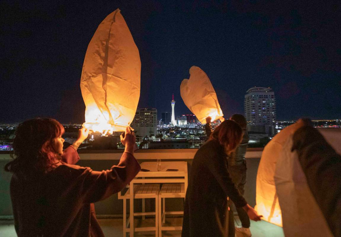 Amber Harlan, of Las Vegas, left, releases a Chinese Lantern from the Juhl apartments in downto ...