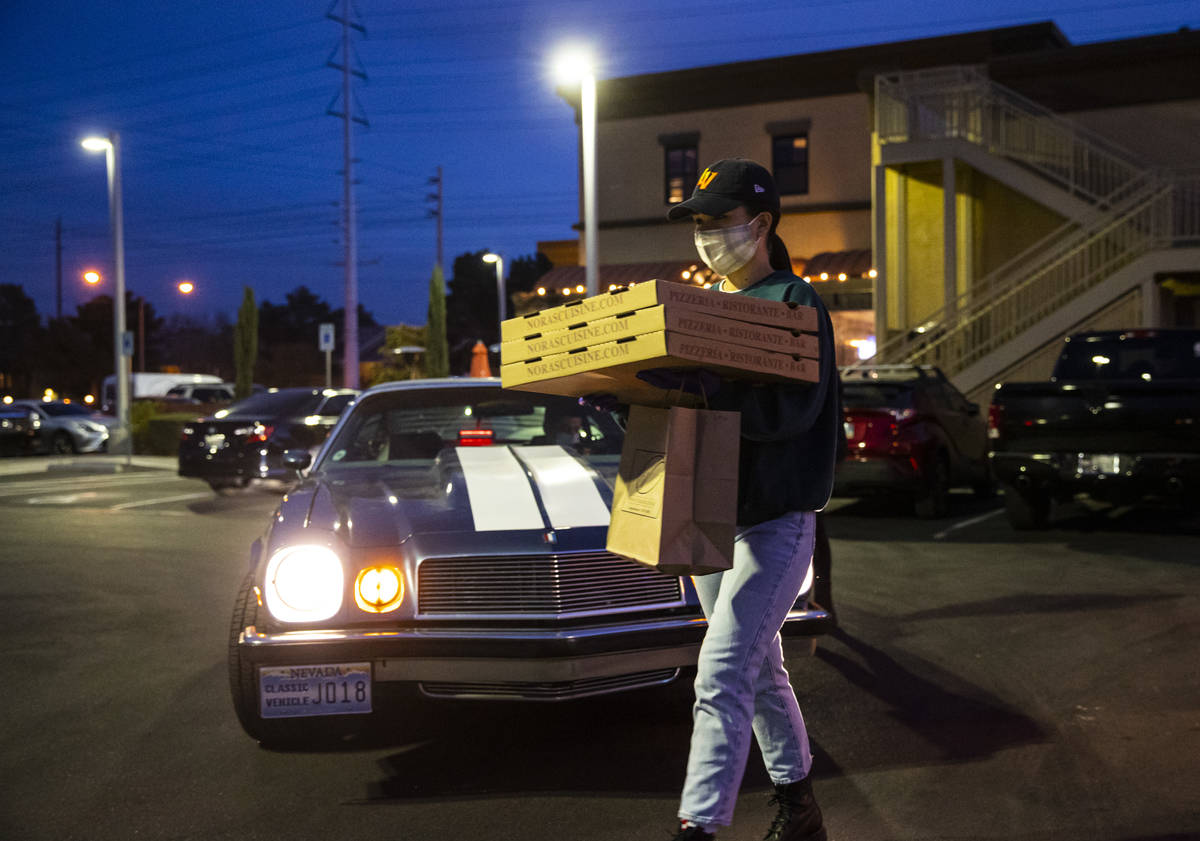 Hostess Emily Mejorada brings out food for curbside pickup at Nora's Italian Cuisine in Las Veg ...