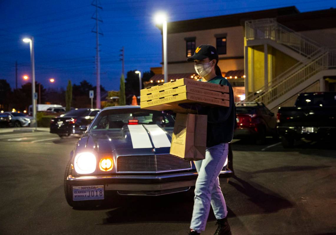 Hostess Emily Mejorada brings out food for curbside pickup at Nora's Italian Cuisine in Las Veg ...