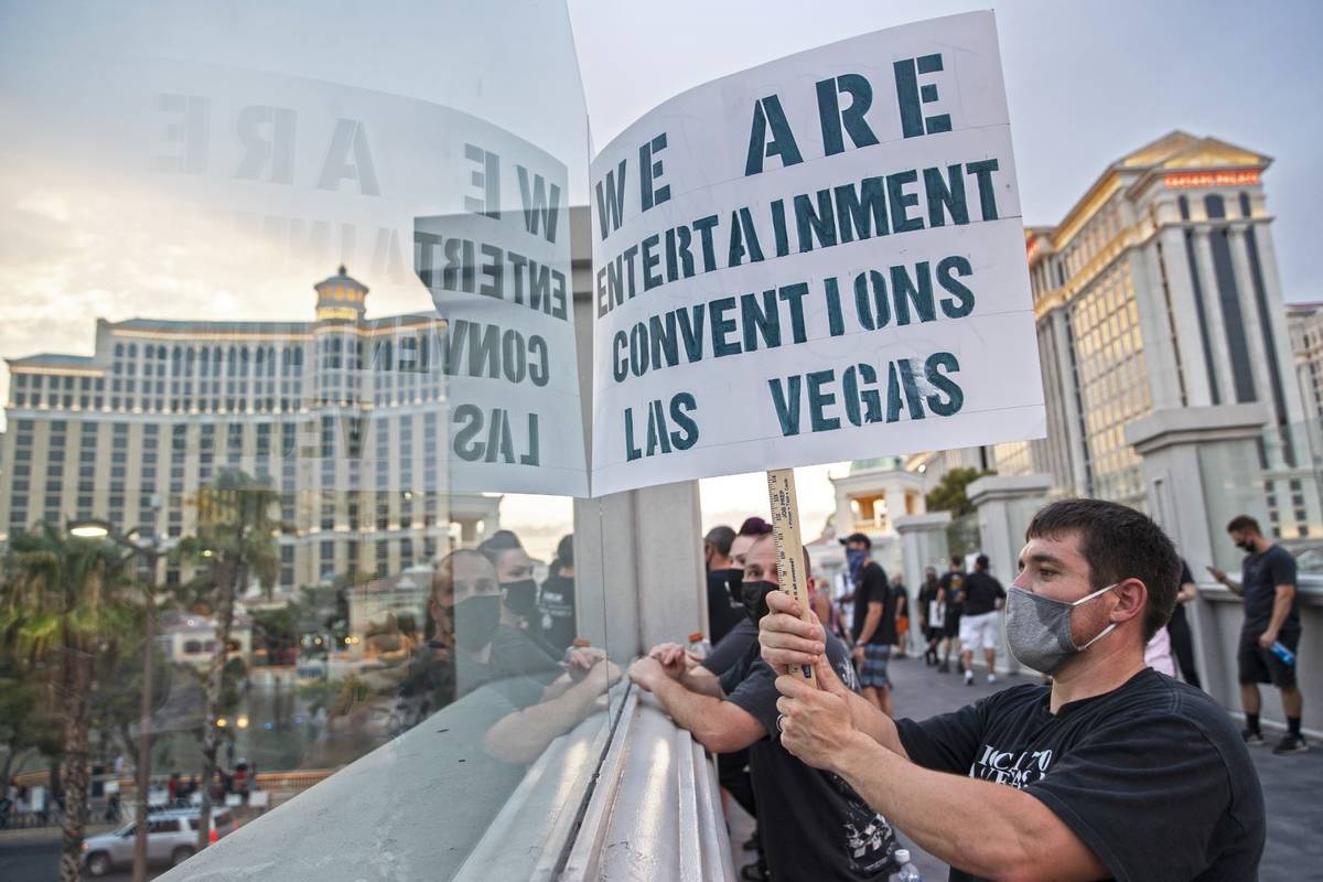 Leandro Esqueda holds a sign on a pedestrian bridge while watching a motorcade of his peers pas ...
