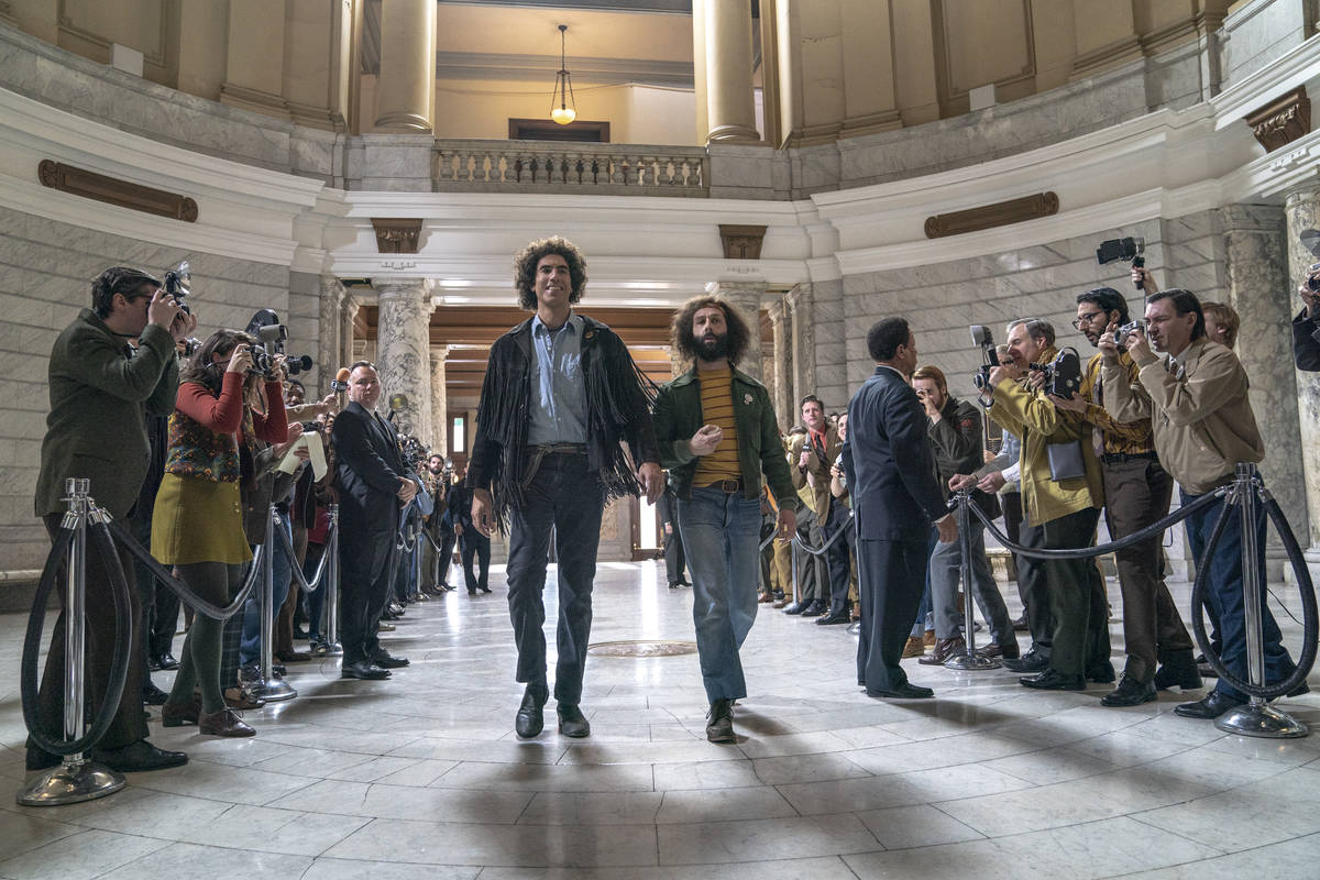 This image released by Netflix shows Sacha Baron Cohen, center left, and Jeremy Strong in a sce ...