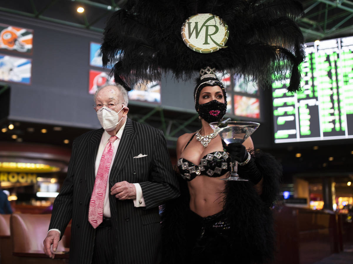 Former Las Vegas Mayor Oscar Goodman, left, is escorted by a showgirl to place his Super Bowl b ...