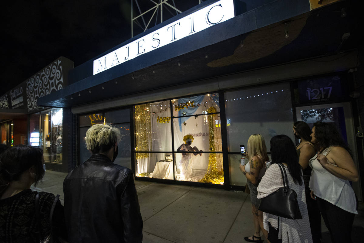 Passersby watch as Heidi Rider performs from the windows of the Majestic Repertory Theatre in t ...