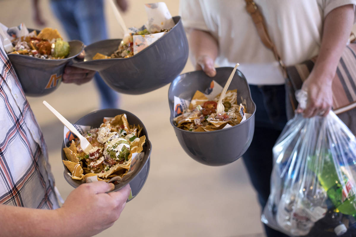 Jason Skrinak and Christie Skrinak juggle sodas and nachos served in baseball helmets to bring ...