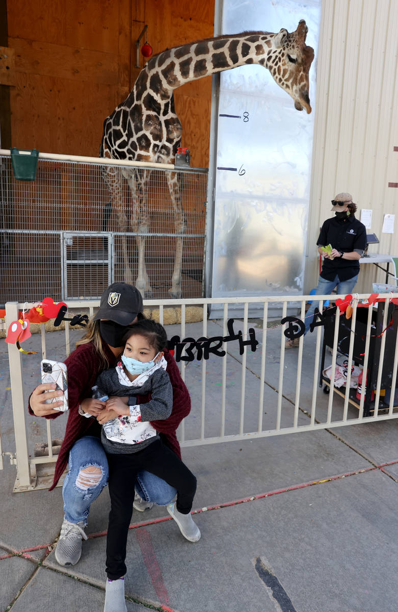 Ozzie the giraffe poses for a photo with Garlene Lao and her daughter Gianna Lao, 4, during a w ...