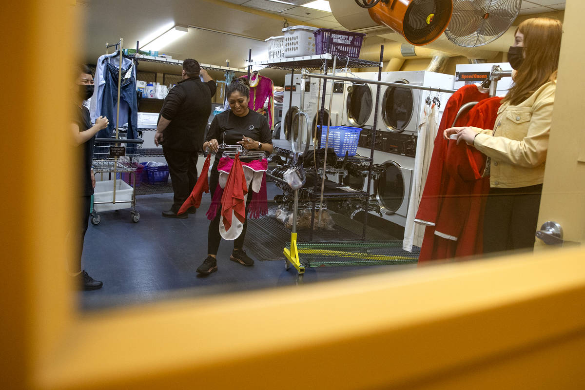 Wardrobe staff readies costumes downstairs while a rehearsal for "O" is underway upst ...
