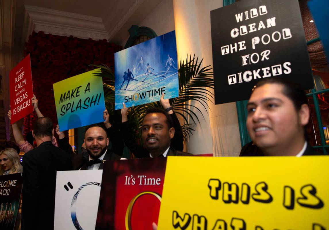 Bellagio employees hold signs alongside a welcome back parade for Cirque du Soleil show "O ...