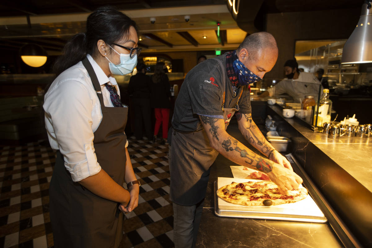 Director of operations Kyle Kingrey prepares a prosciutto flat bread as food runner Kassandra D ...