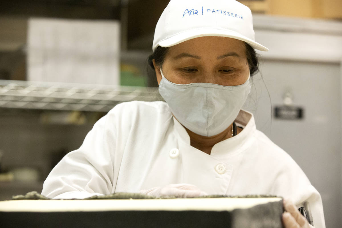 Member of the Aria pastry team Nghia Mai trims fondant icing on part of a Raiders-themed cake a ...