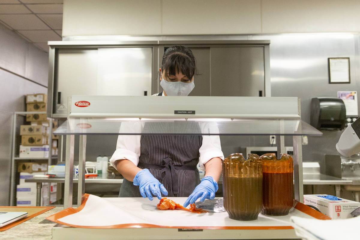 Assistant pastry chef Andy Madrid kneads the orange molten sugar that will become a flame for a ...