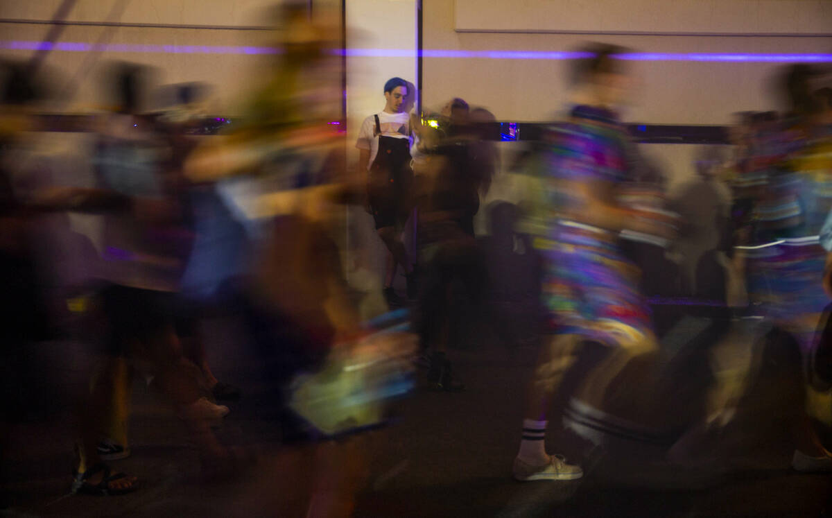 Attendees stream along a neon-lit alleyway during day one of Life is Beautiful on Friday, Sept. ...