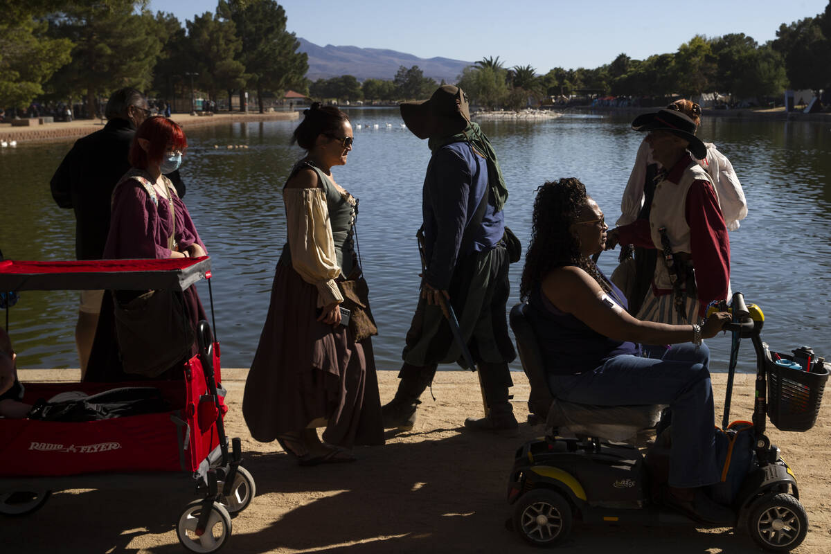 Pedestrians mill about Sunset Park, the venue for the Age of Chivalry Renaissance Festival on S ...