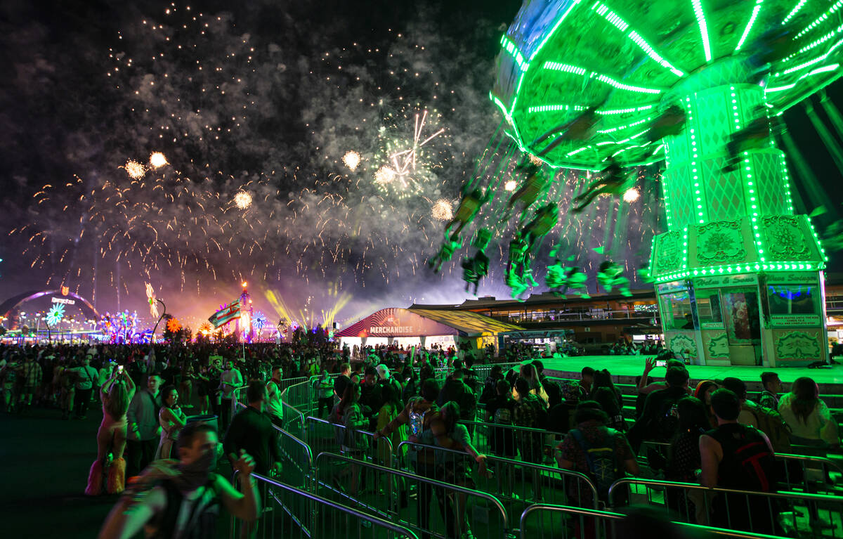 Attendees swing on a carnival ride as fireworks go off across the festival grounds during the s ...