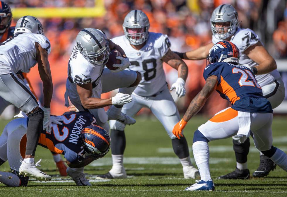 Raiders' running back Kenyan Drake (23) is upended by Denver Broncos safety Kareem Jackson (22) ...