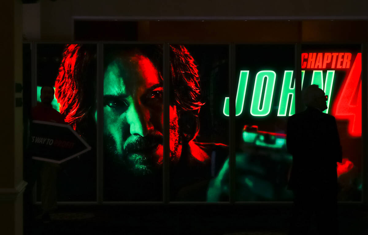 An attendee walks by a display for “John Wick: Chapter 4” at the CinemaCon trade ...