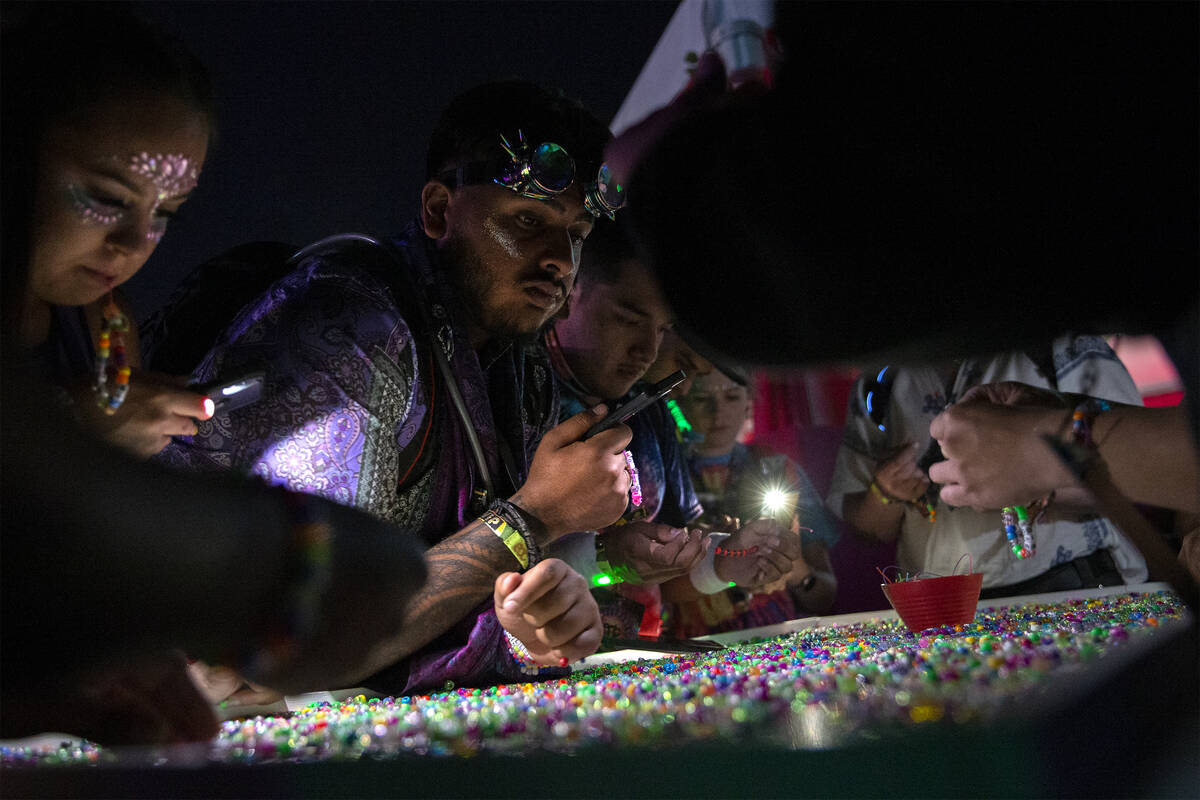 Electric Daisy Carnival attendees make beaded bracelets during the first day of the electronic ...