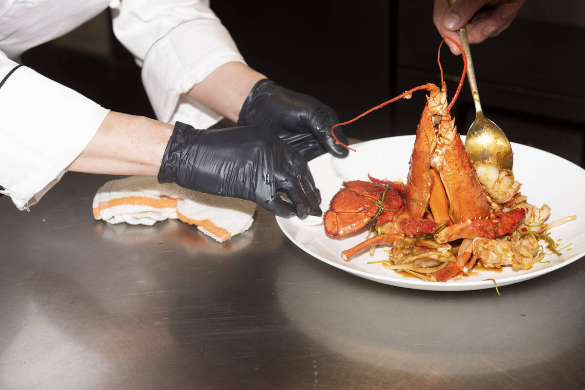 Chef Yip Cheung, left, wipes off the plate while a member of the kitchen staff prepares the Sti ...