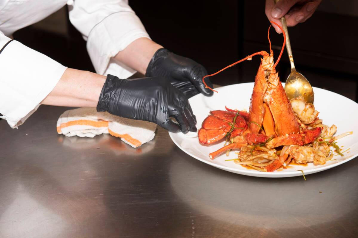 Chef Yip Cheung, left, wipes off the plate while a member of the kitchen staff prepares the Sti ...