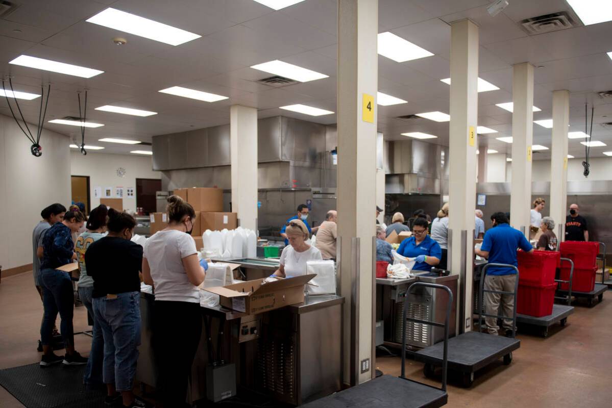 Volunteers help pack lunches for students on summer break at Three Square, the food bank servin ...