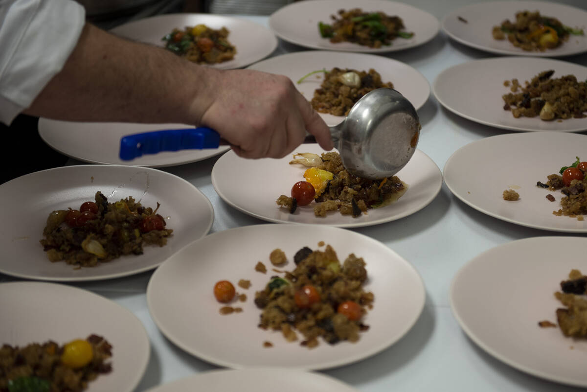 Chef Jeffrey Weiss plates the fourth dish, roast pork presa with Benton’s bacon migas and piq ...