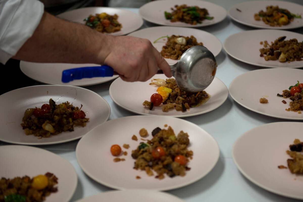 Chef Jeffrey Weiss plates the fourth dish, roast pork presa with Benton’s bacon migas and piq ...