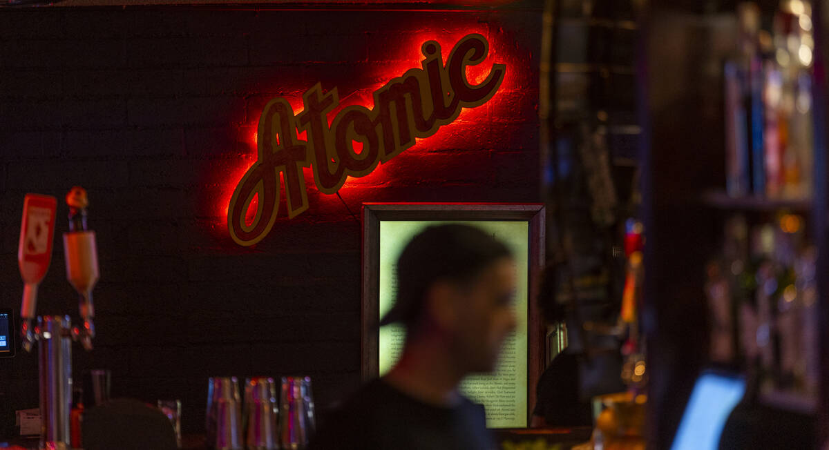 The bar lighting is dark and colorful as usual during the start of the Atomic Liquors 70th anni ...