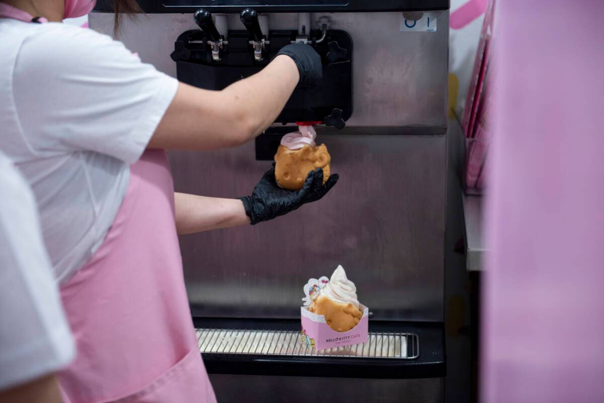 and employee pours the ice cream for the cafe's signature treat, soft served ice cream inside a ...