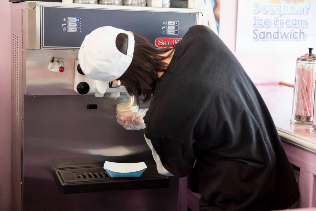 Cream Me Ice Creamery employee Axel Vega serves ice cream at the shop on Main Street in the Art ...